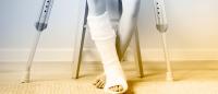 Child with cast on lower leg sitting with crutches